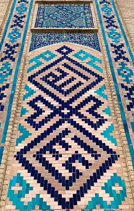 Detail of blue and turquoise geometric ceramic mosaic on a decorated wall, typical of Islamic architecture in Uzbekistan.